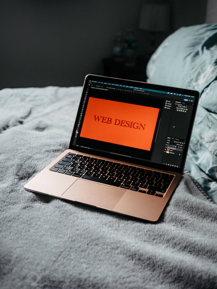 why-choose-us A laptop on a bed showing web design software, creating a cozy workspace.